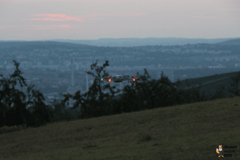 Die DJI Air 2S fliegt bei Dämmerung und die LEDs an den Armen der Propeller leuchten auf.